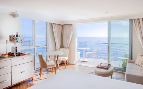 a room with a bed and chairs and a glass door