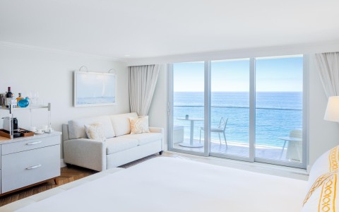 a room with a bed and a couch and a sofa with a view of the ocean