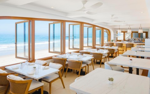 a room with tables and chairs and a view of the ocean