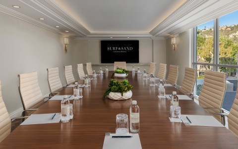 a conference room with chairs and a table with water bottles and a screen