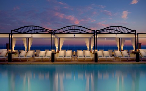 view of the outdoor pool and pool deck at night