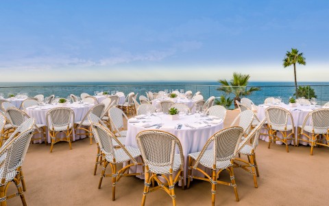 a group of tables and chairs outside with a body of water in the background