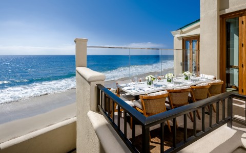 a table set for dinner on a balcony overlooking the ocean