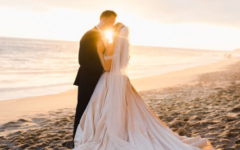 Newlyweds in front of the ocean at sunset