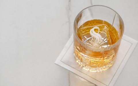 a glass of liquid with a letter on top