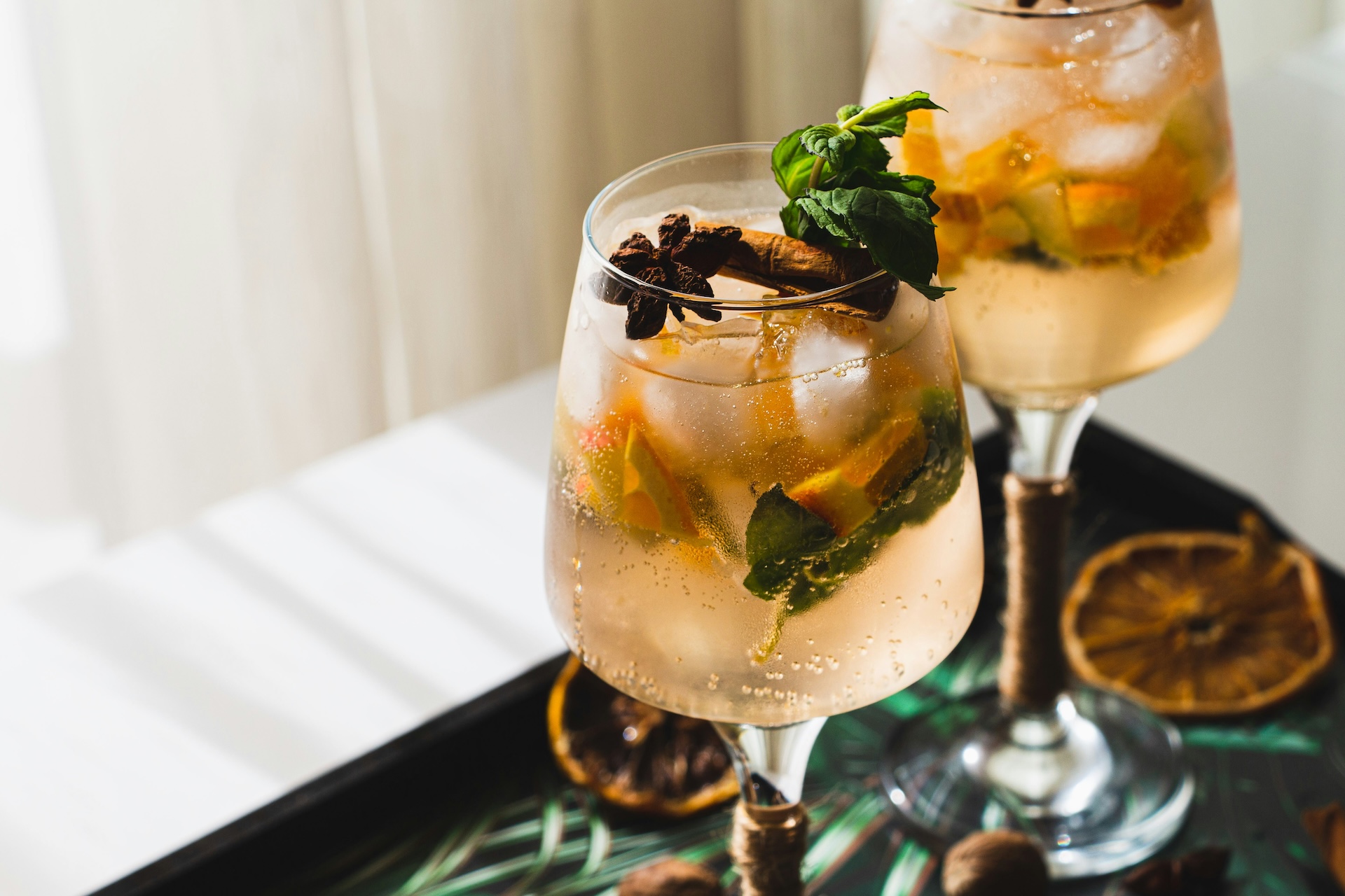 two glasses of liquid with fruit and leaves on them
