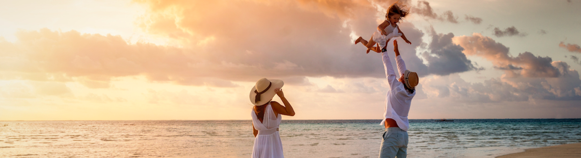 a woman in a white dress and hat on a beach