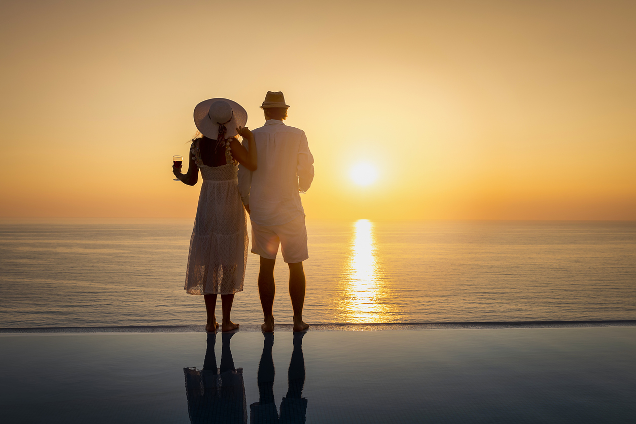 a man and woman standing on a pool with a sunset in the background