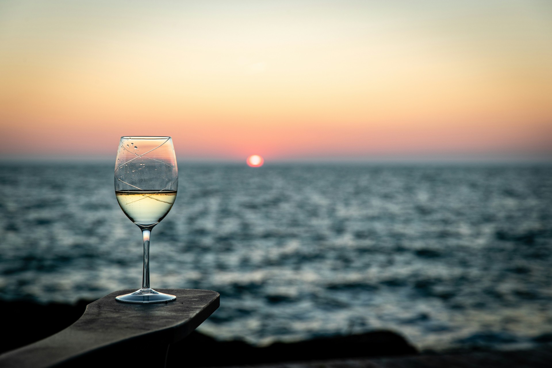 a glass of wine on a table with a sunset in the background