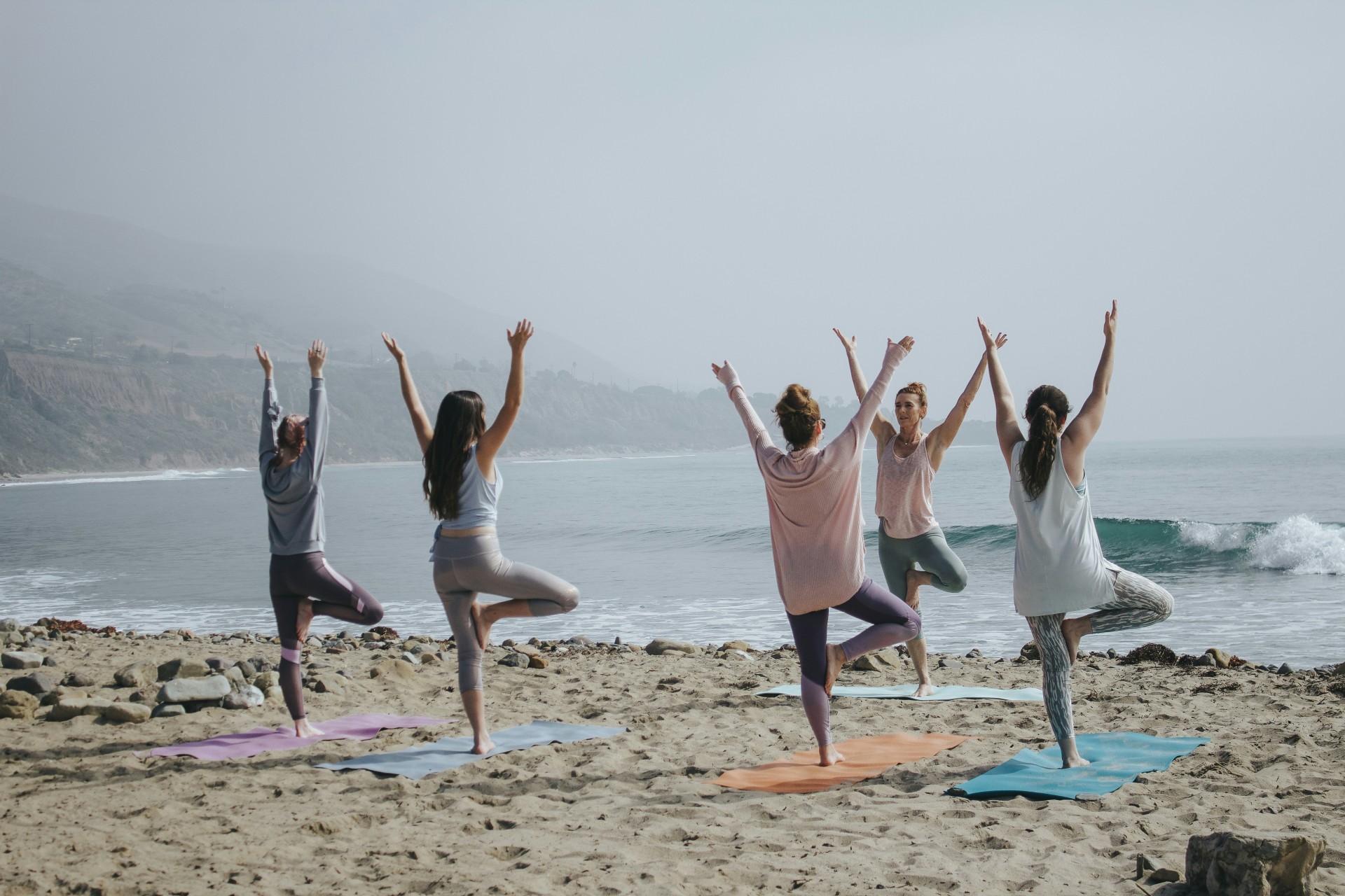 a group of people doing yoga on the beach