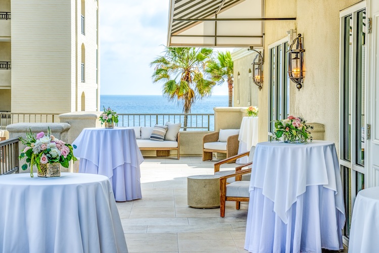 a patio with tables and chairs and a view of the ocean