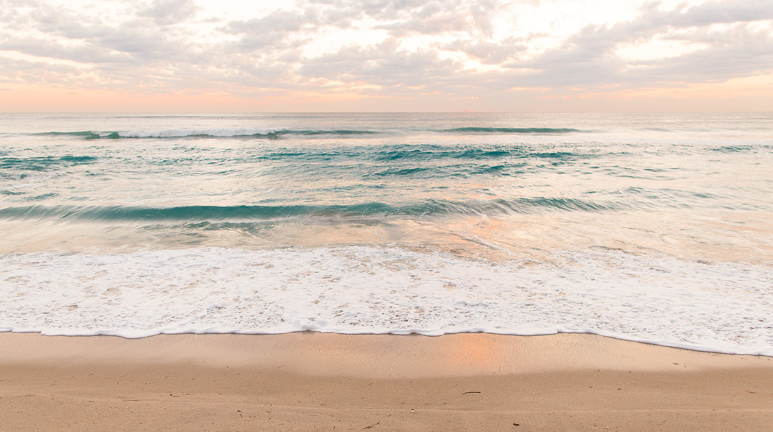 a beach with waves and clouds