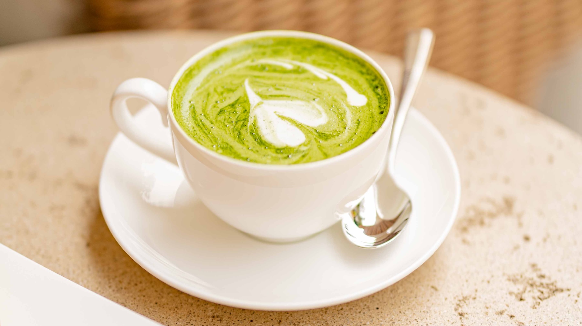 a cup of green drink with a spoon