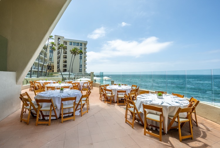 a restaurant with tables and chairs on a patio overlooking the ocean