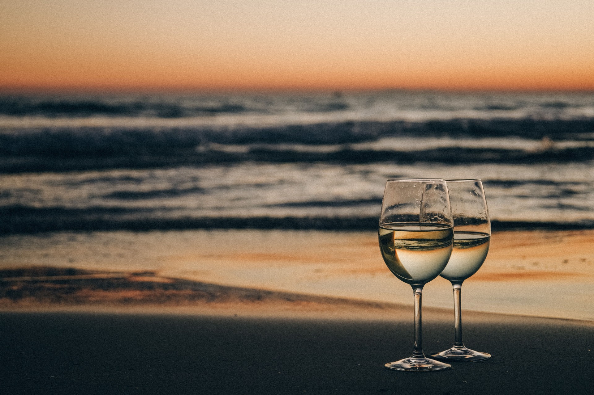 two wine glasses on a beach