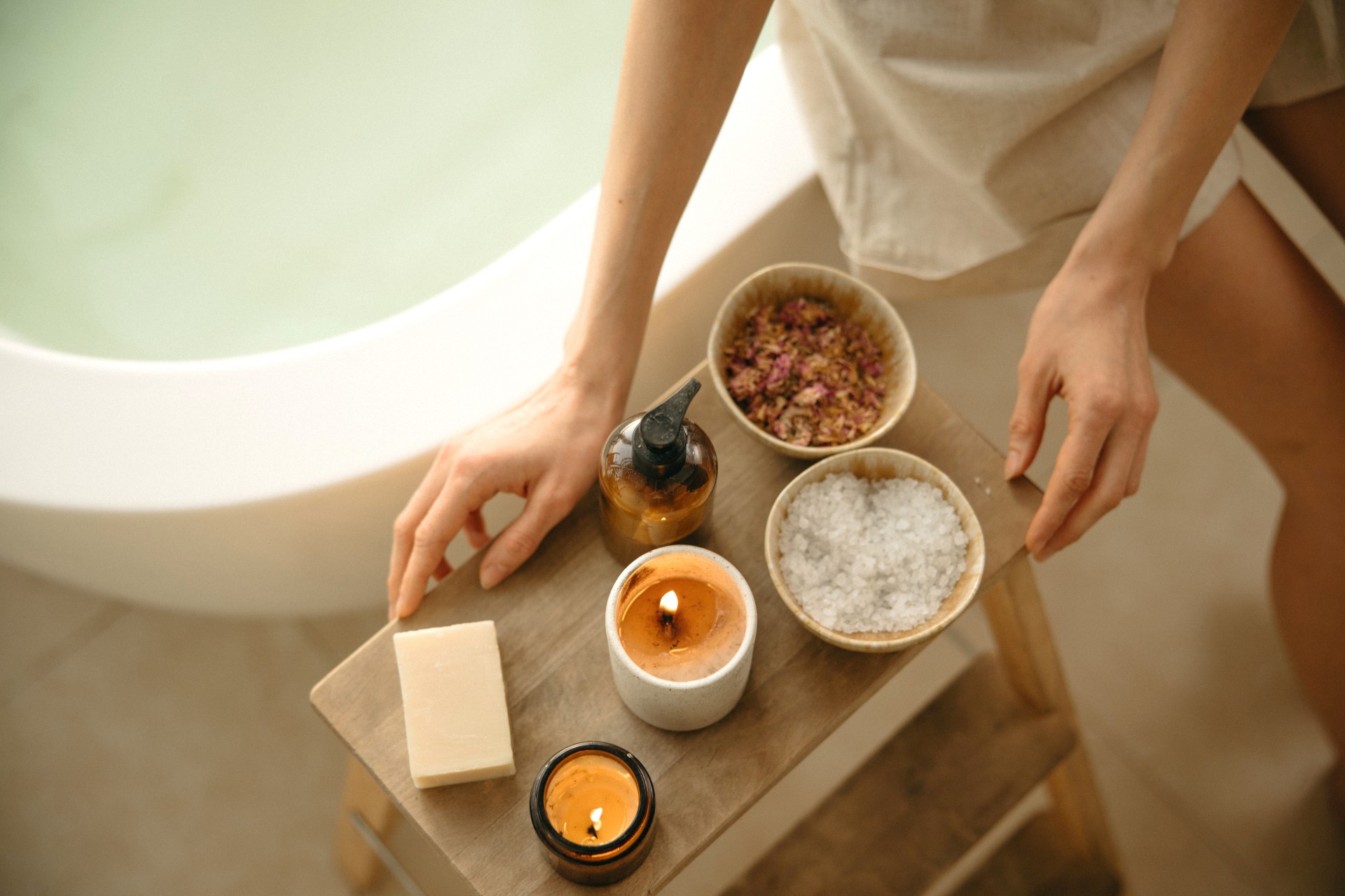 a person standing on a stool with a tray of candles and a bowl of salt