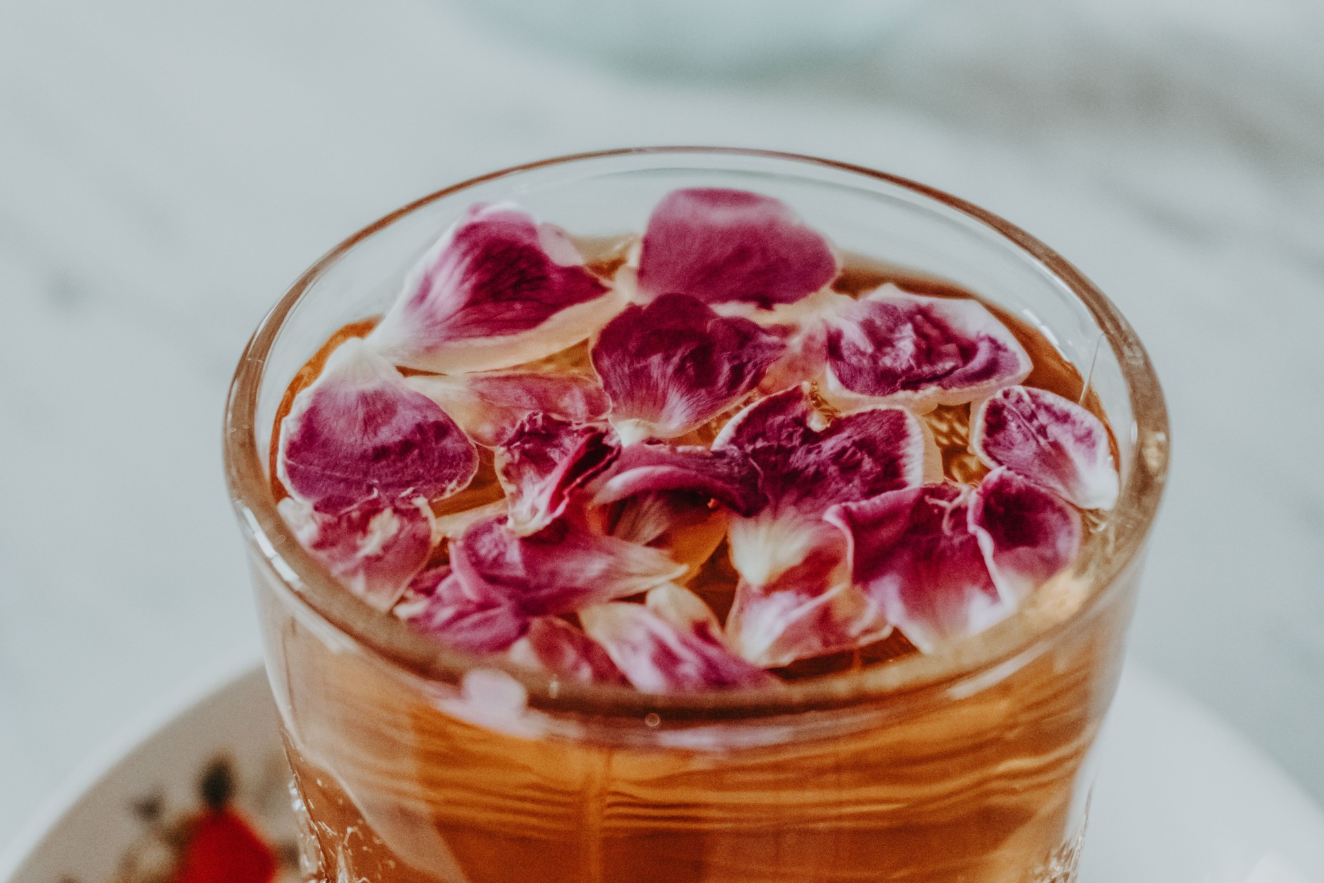 a glass with a drink filled with liquid and flowers