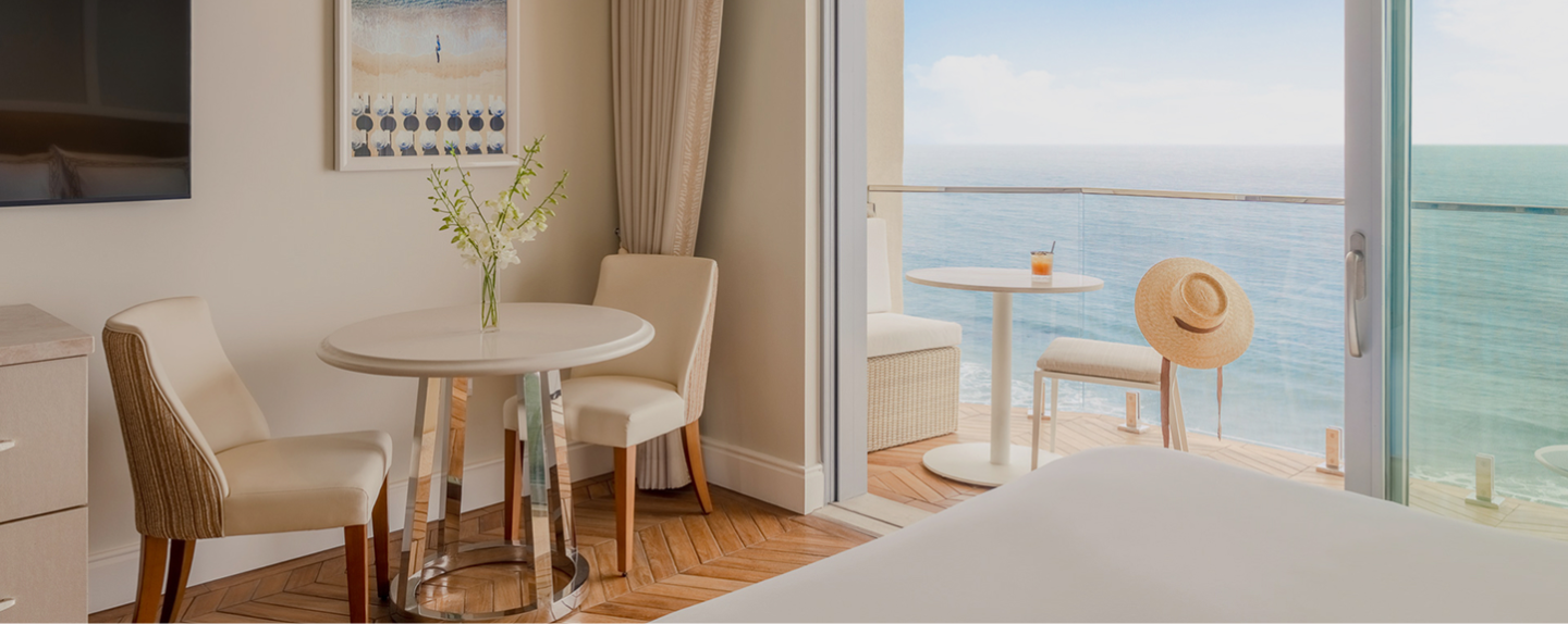 a room with a table and chairs and a view of the ocean