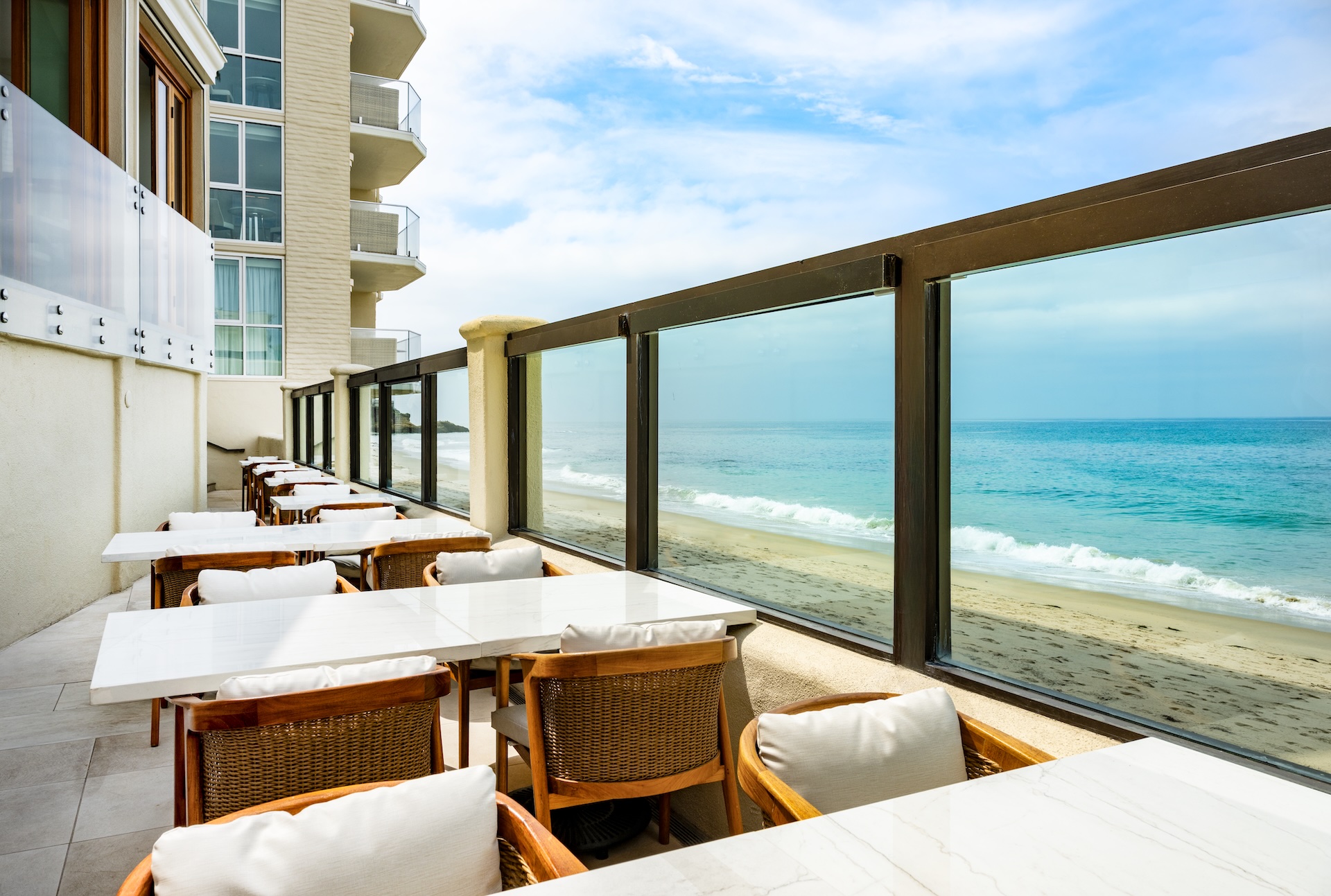 a beachfront restaurant with chairs and a glass railing