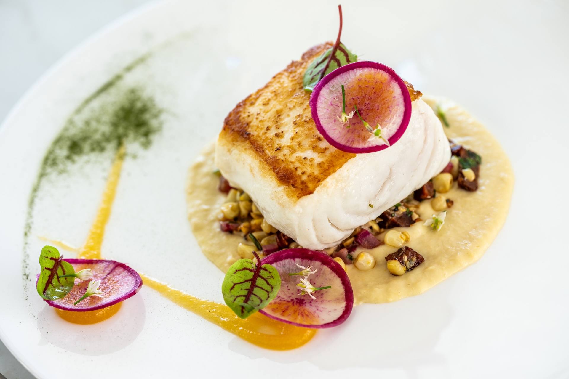 a piece of fish with vegetables on a white plate