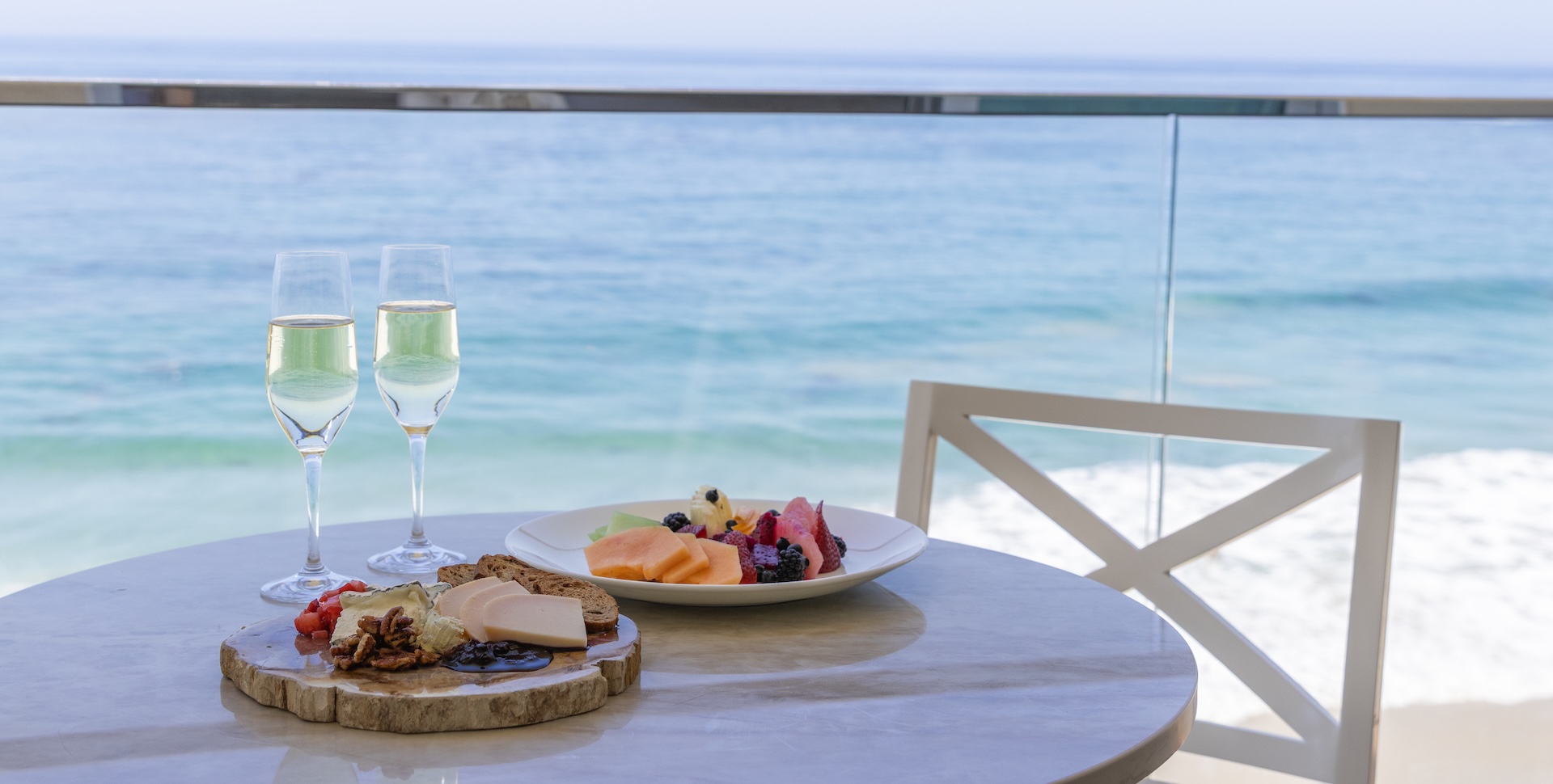 a plate of fruit and cheese on a table with a glass of wine