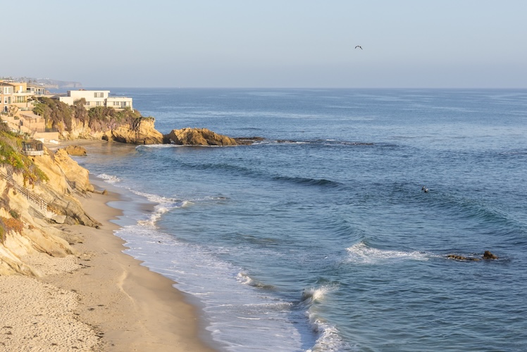a beach with a house and a body of water