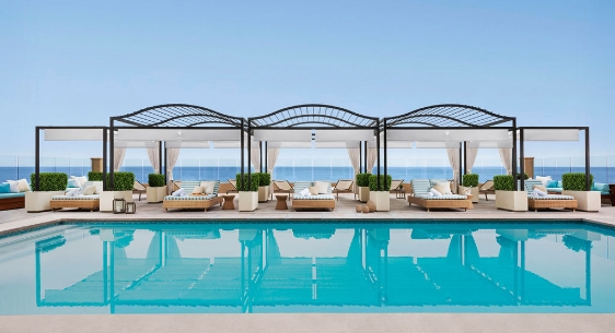 a pool with lounge chairs and a large body of water