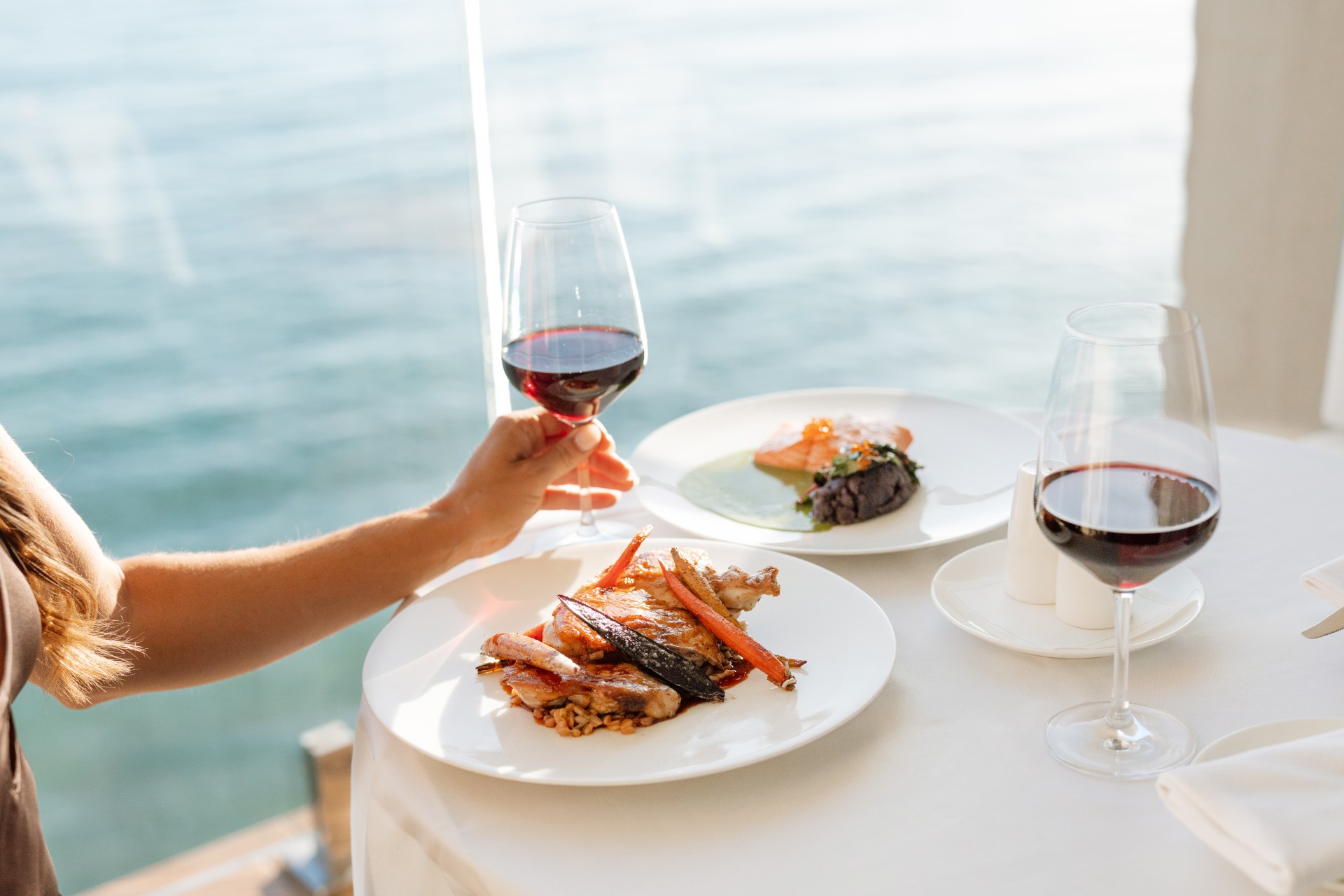 a hand holding a glass of wine and a plate of food