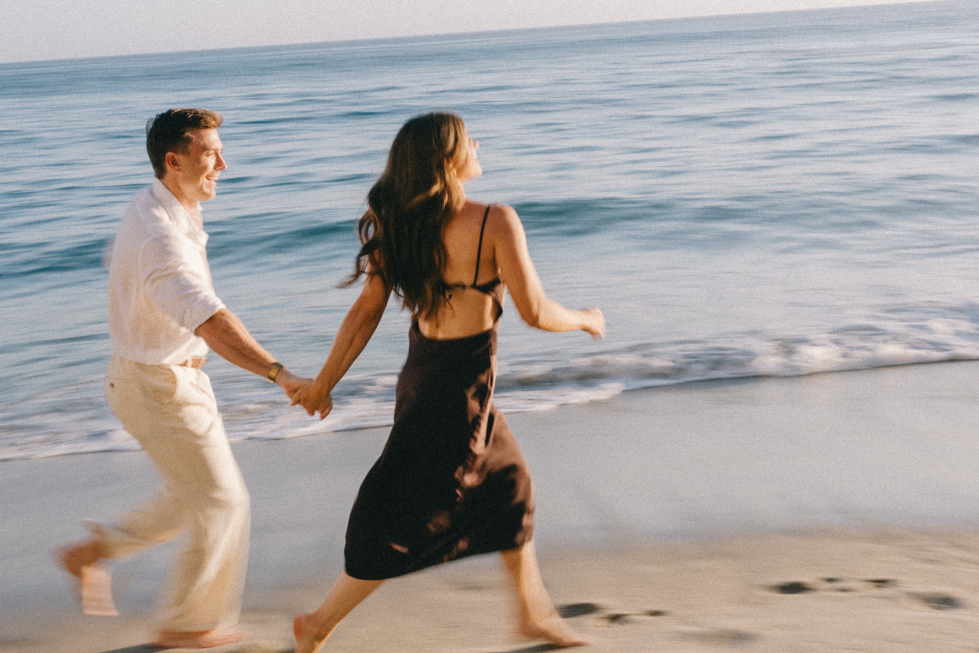 a man and woman holding hands on a beach