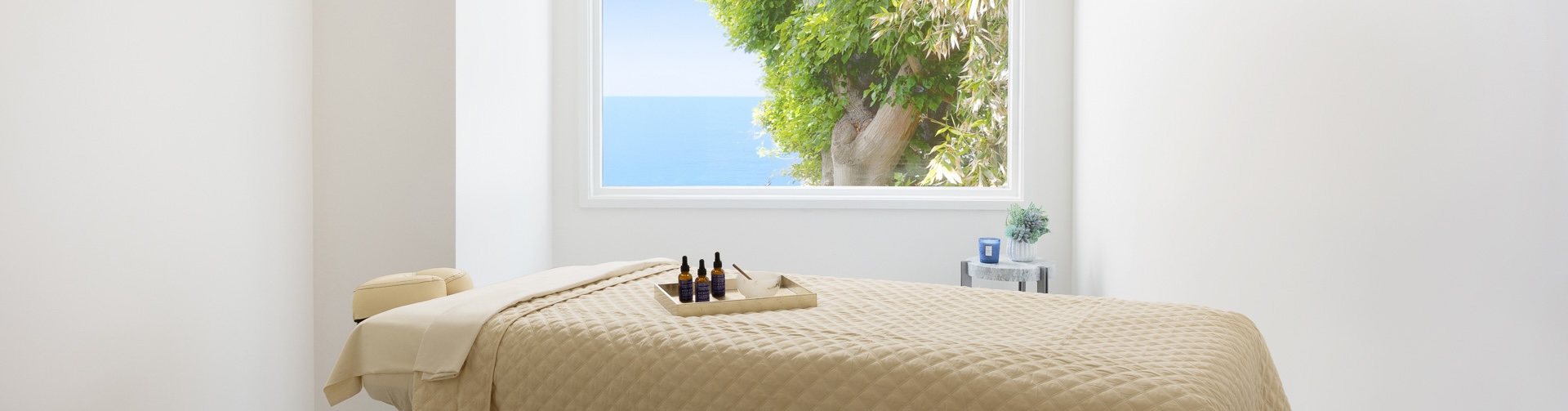a bed with a tray of essential oils and a bowl of water outside