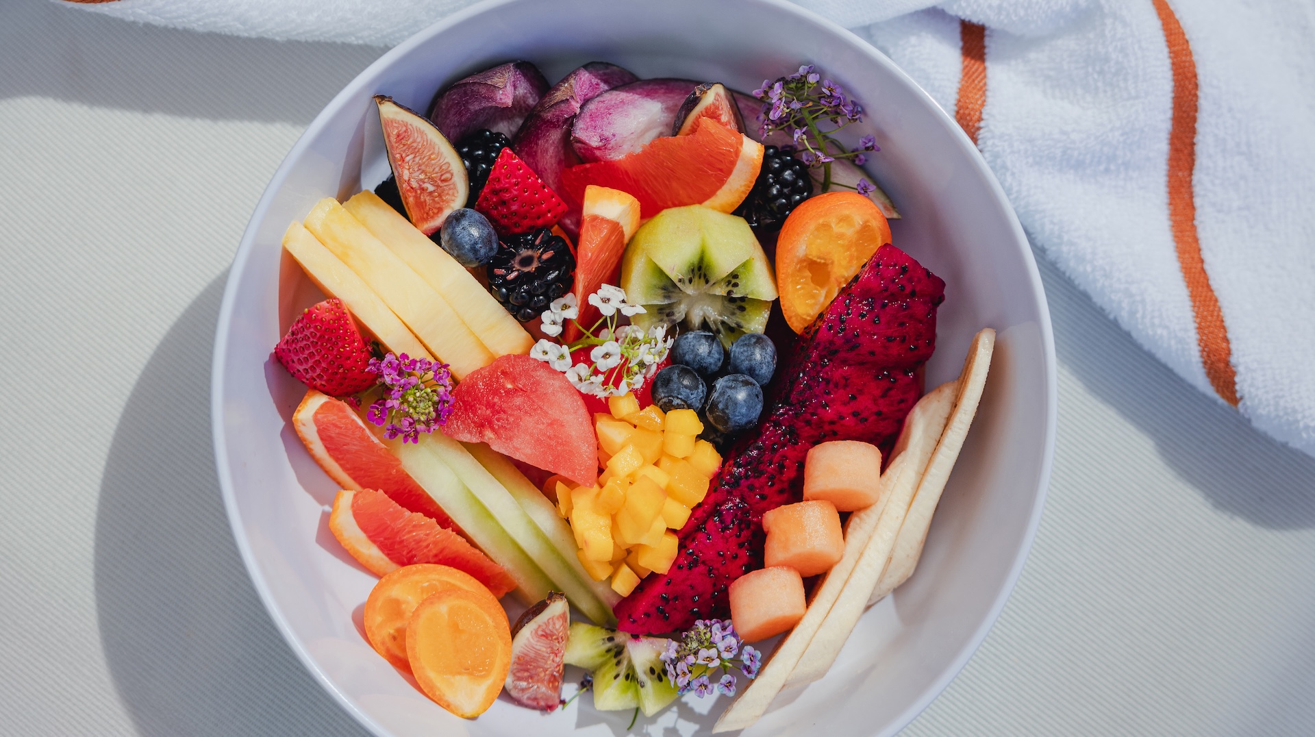 a bowl of fruit and flowers