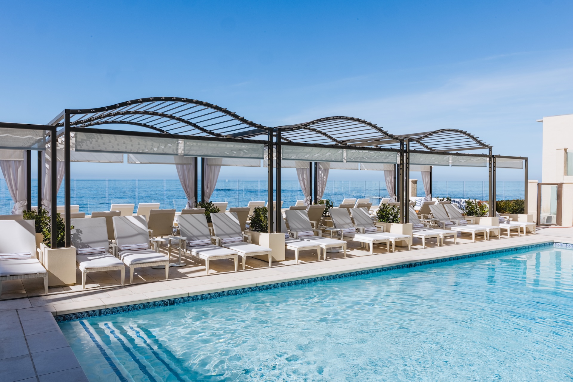 a pool with lounge chairs and a covered area
