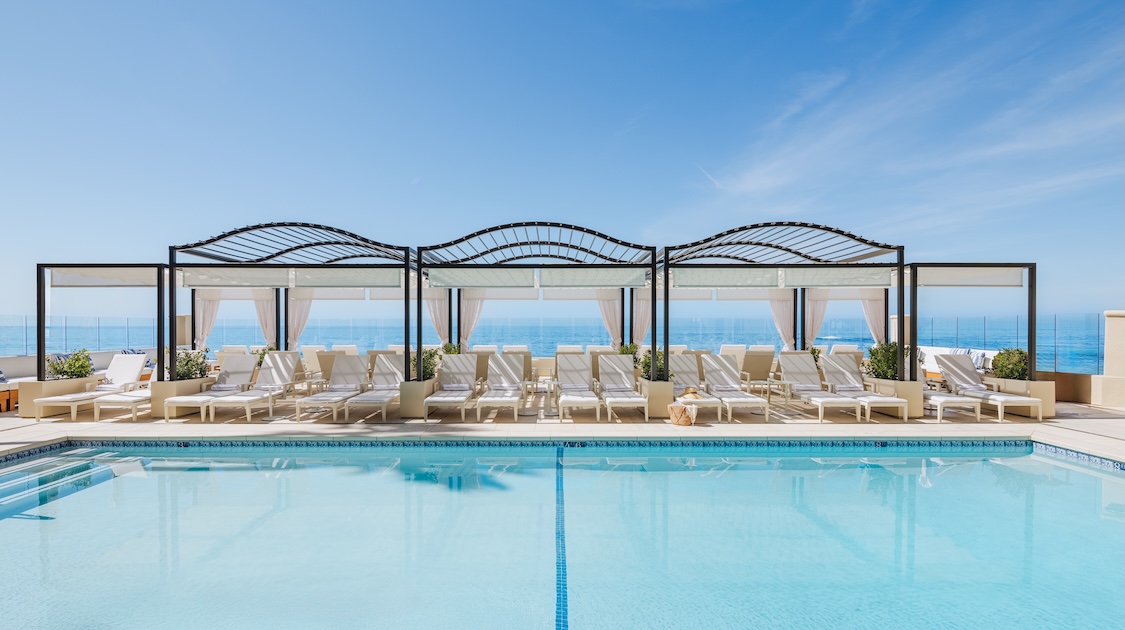 a pool with lounge chairs and a large body of water