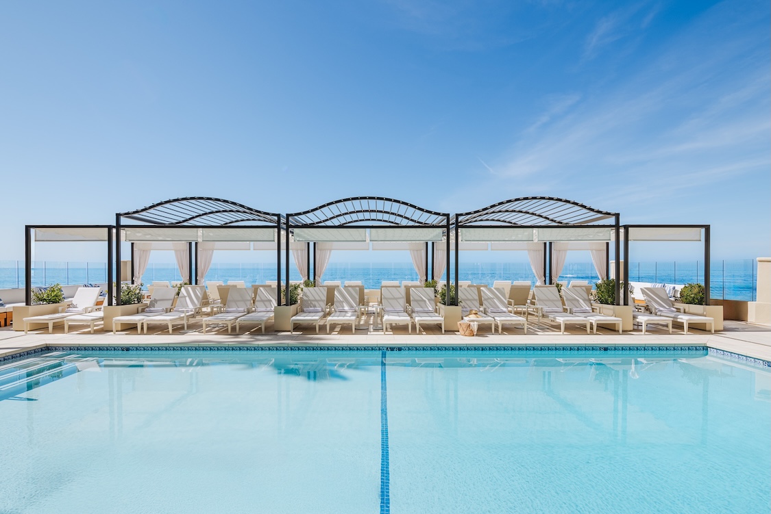 a pool with lounge chairs and a large body of water