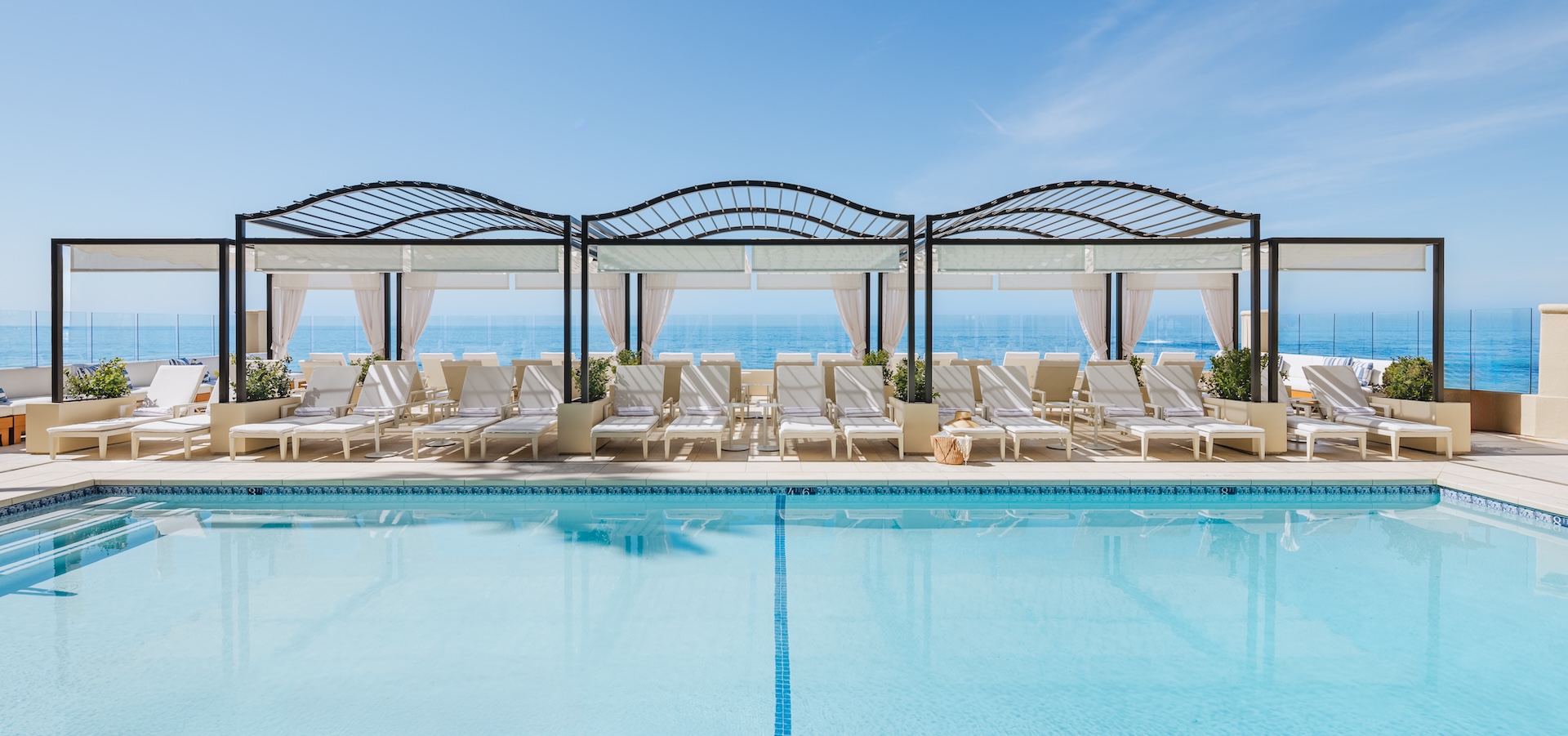 a pool with lounge chairs and a large body of water