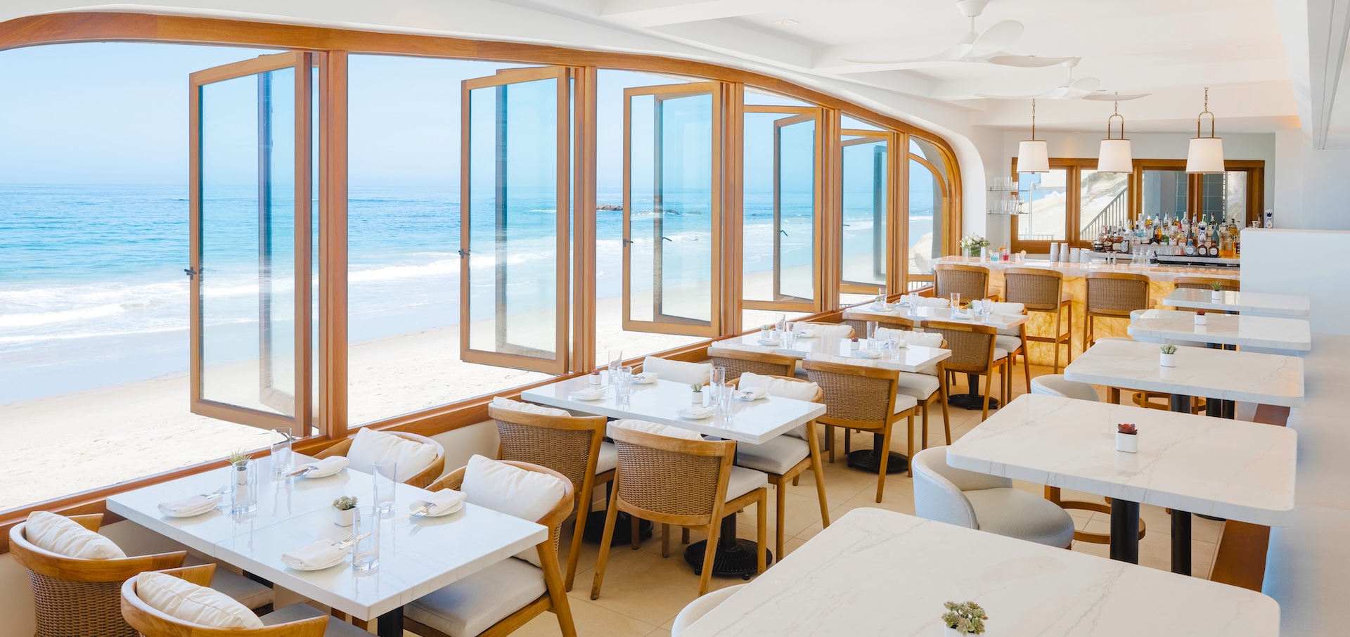 a room with tables and chairs and a beach view