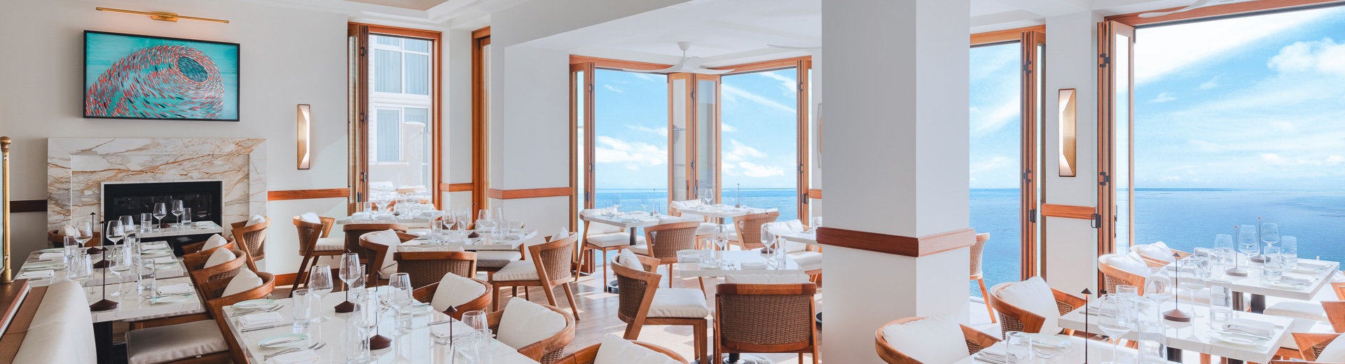 a room with tables and chairs and a view of the ocean