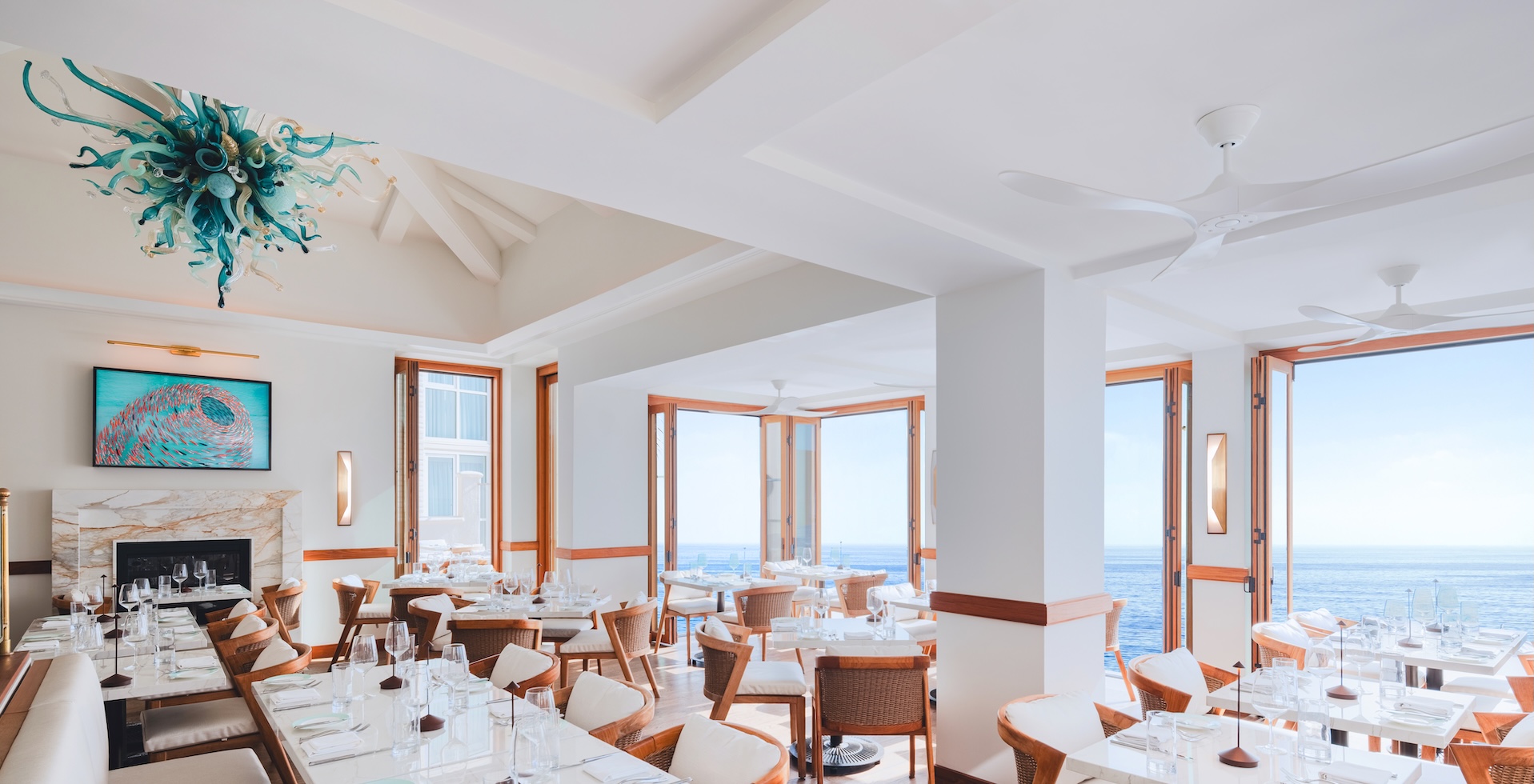 a room with tables and chairs and a view of the ocean