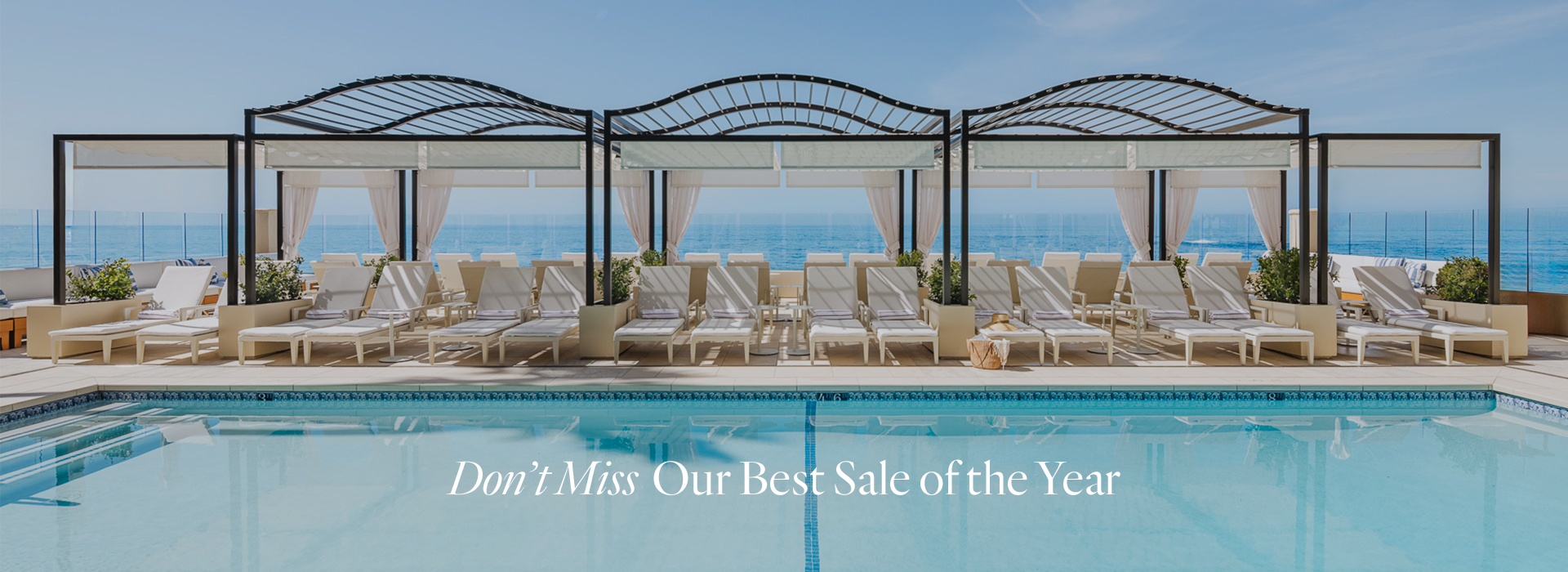 a pool with lounge chairs and a large body of water