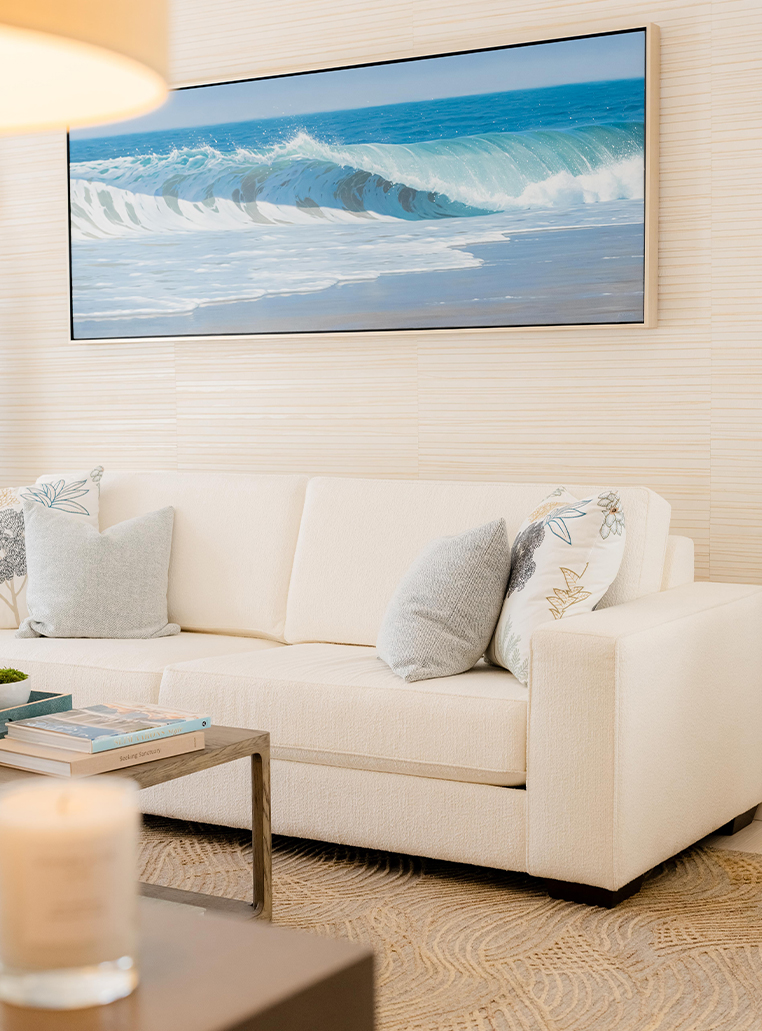 a white couch with pillows in front of a painting