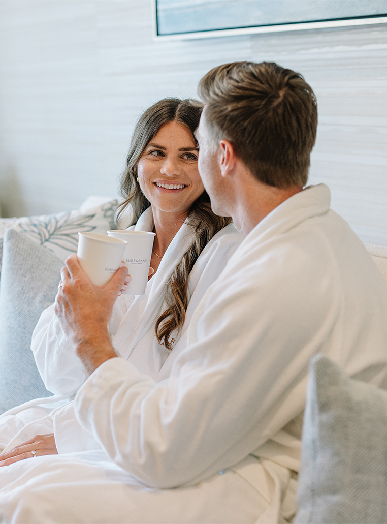a man and woman in bathrobes holding cups