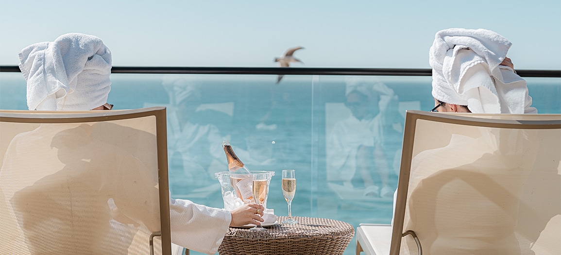 a person sitting at a table with a bucket of champagne and two glasses of champagne
