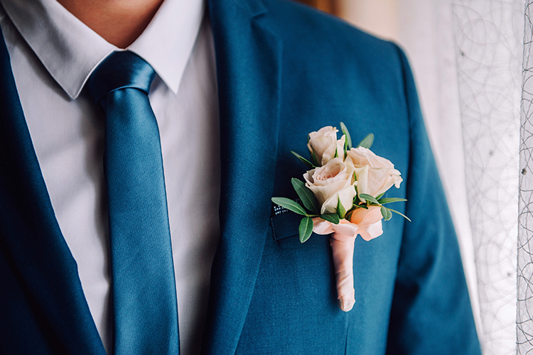 up close view of boutonniere on a man with a blue tuxedo 
