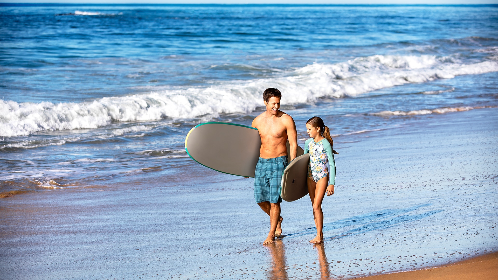 a couple walking on the beach with their surfboards
