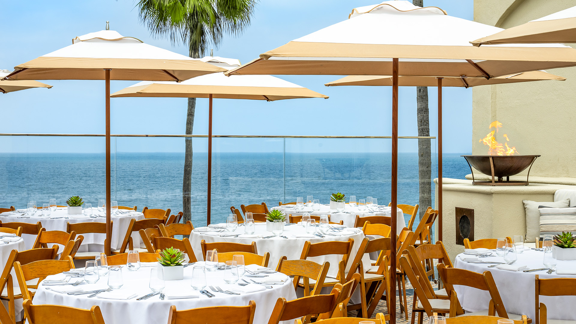 a tables and chairs with umbrellas and palm trees