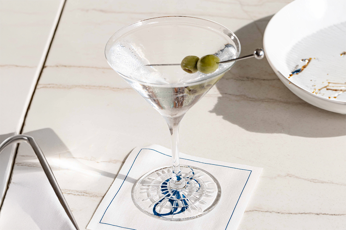 a martini glass with olives on a white napkin