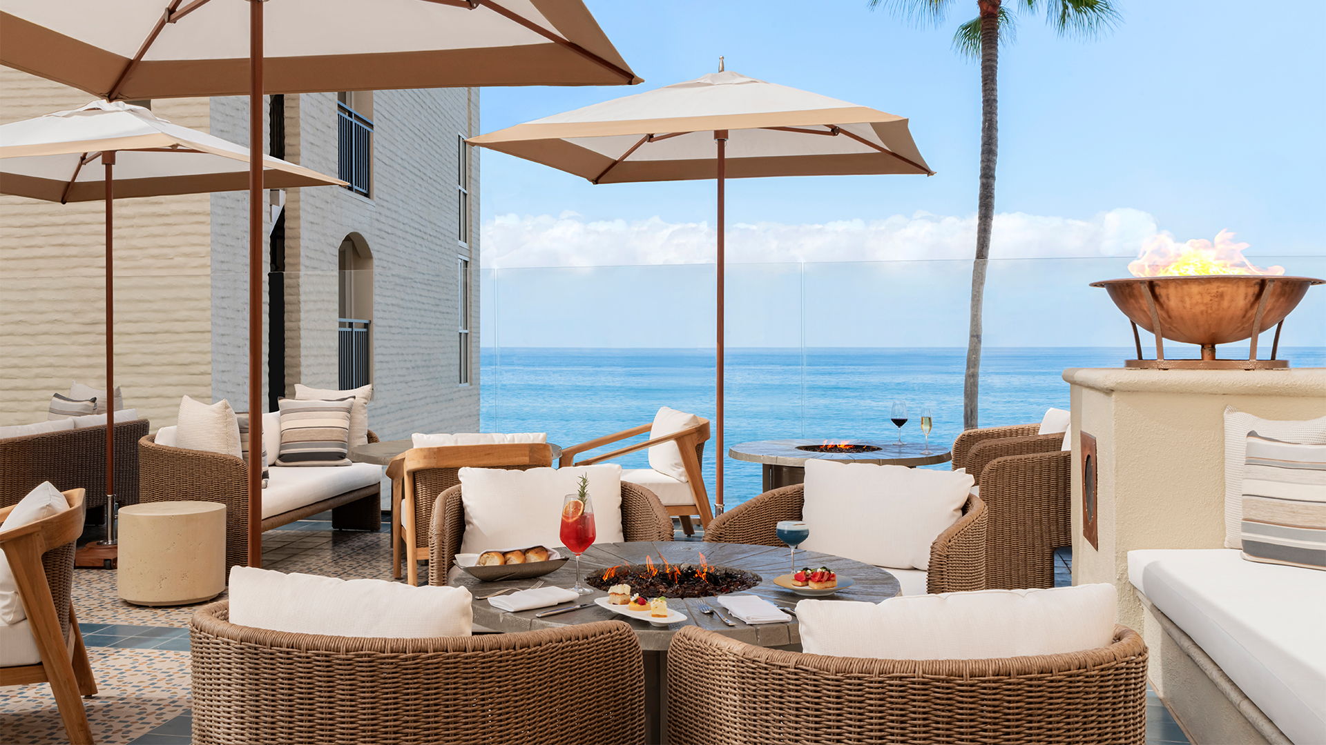 a patio with a fire pit and chairs and a palm tree