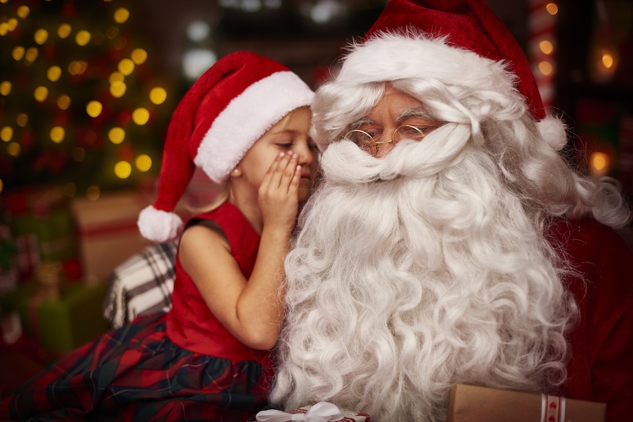 a girl whispering to a man in a santa garment