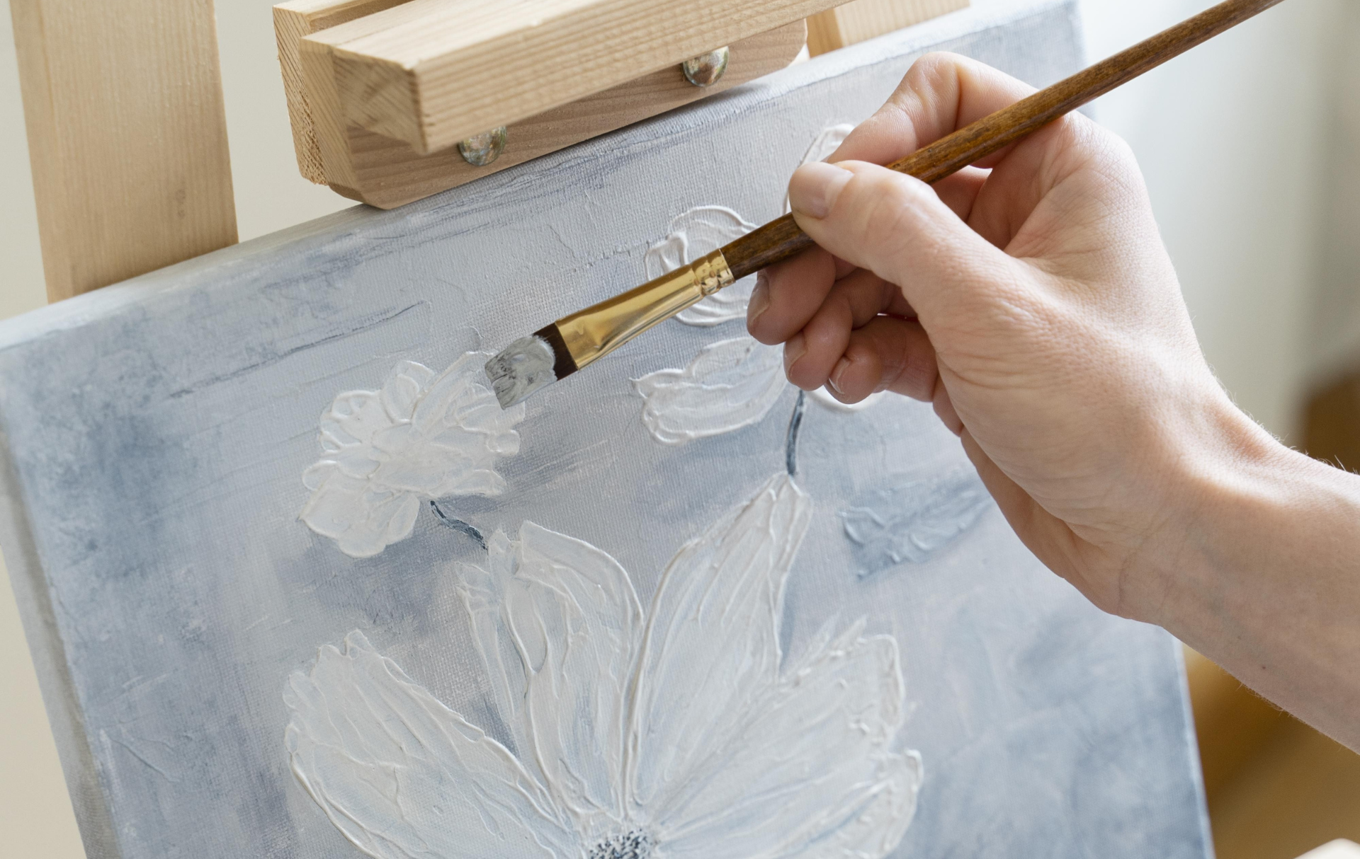 a hand holding a paintbrush over a painting