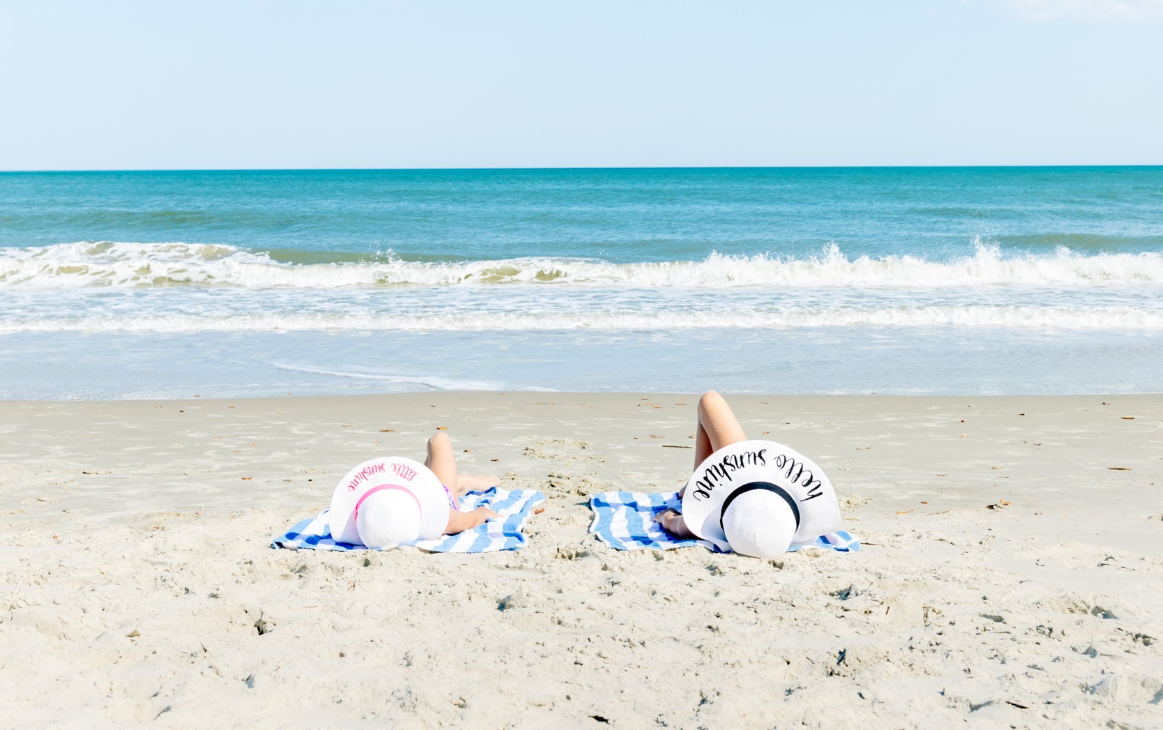 two people lying on towels on a beach